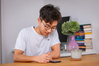 A man looks down at his phone, while listening to Bible in One Year